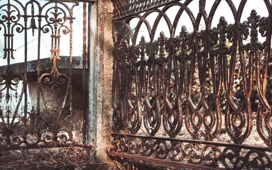 A weathered steel gate beside a stone wall