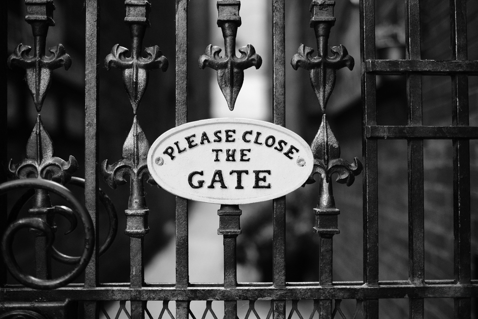 A weathered steel gate beside a stone wall